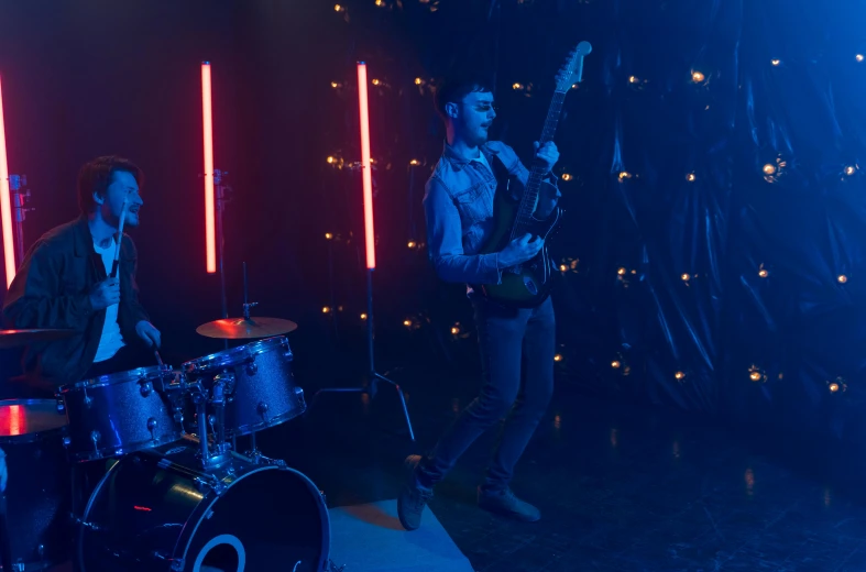 a couple of men standing next to each other on a stage, an album cover, pexels, high blue lights, guitarist, charli bowater, movie action still frame