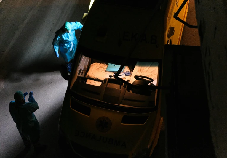 a man standing on the side of a road next to a truck, by Adam Marczyński, pexels contest winner, hurufiyya, on an operating table, lit from above, masked doctors, yellow overall