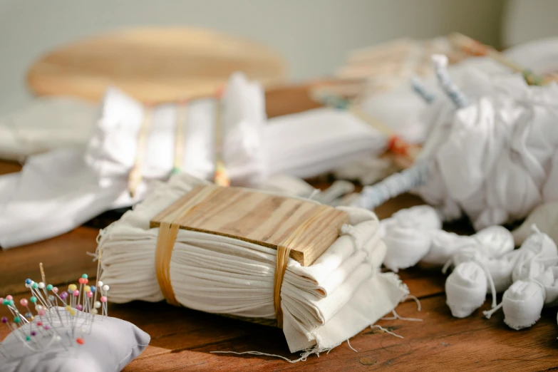 a bunch of sewing supplies sitting on top of a wooden table, inspired by Sarah Lucas, unsplash, arte povera, covered in bandages, white hanfu, 4 0 0 0 samples, close-up product photo