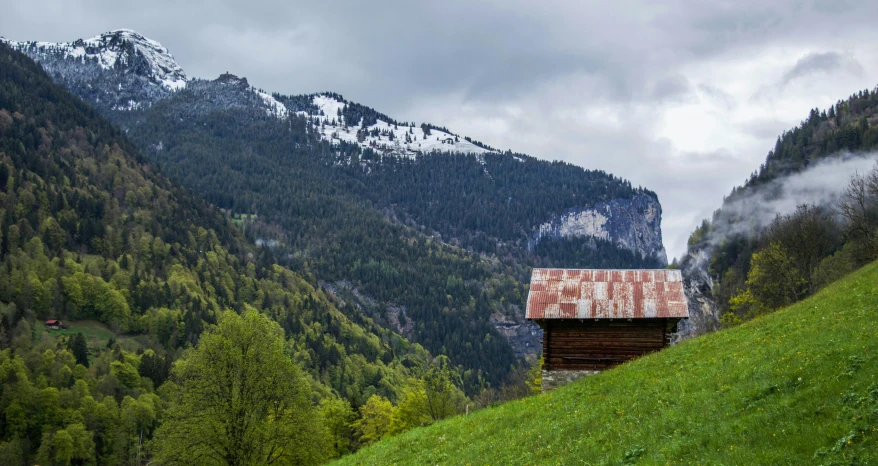 a small cabin sitting on top of a lush green hillside, an album cover, inspired by Peter Zumthor, pexels contest winner, renaissance, lauterbrunnen valley, barn, conde nast traveler photo, urban surroundings