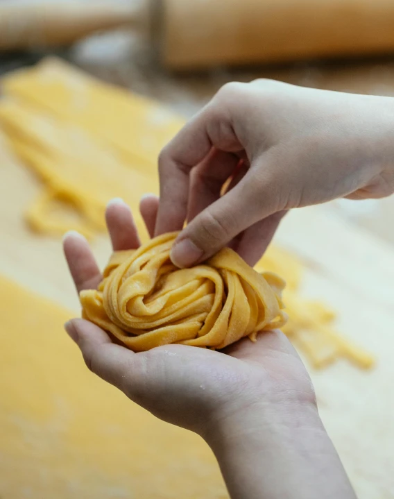 a person holding a piece of pasta in their hand, weave, instagram post, yellow, no cropping