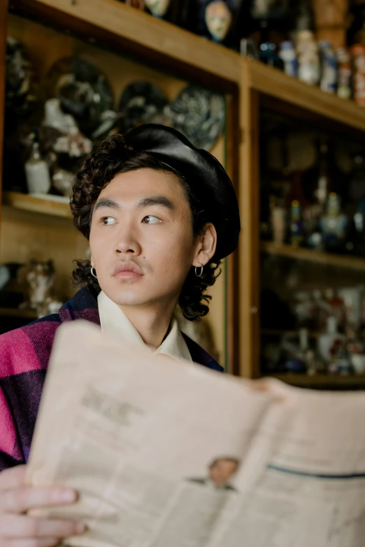 a man sitting at a table reading a newspaper, an album cover, inspired by Fei Danxu, unsplash, an oversized beret, robert sheehan, asian face, traditional chinese clothing