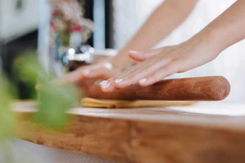 a close up of a person rolling dough on a table, trending on pexels, elegant up to the elbow, natural wood top, white, cooking