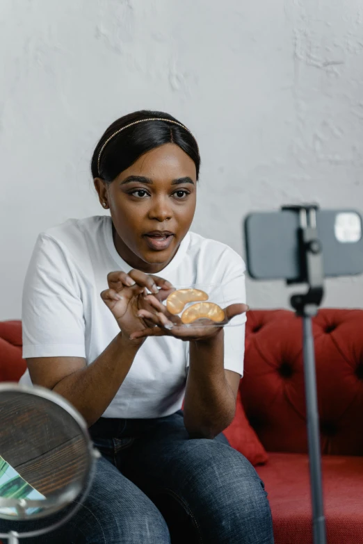 a woman sitting on a red couch holding a donut, a portrait, pexels contest winner, phone recording, holding toasted brioche bun, tessa thompson, cooking show