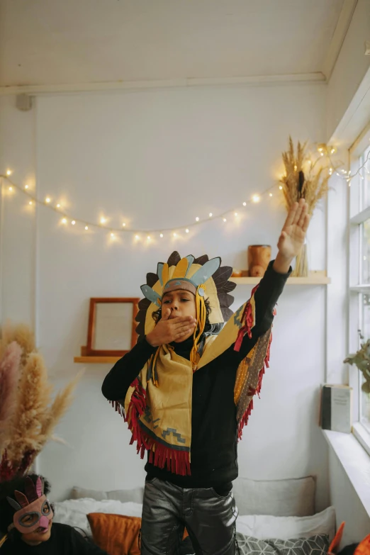 a man standing on top of a bed next to a window, a cartoon, trending on pexels, renaissance, feather native american headgear, wearing festive clothing, holding his hands up to his face, lights