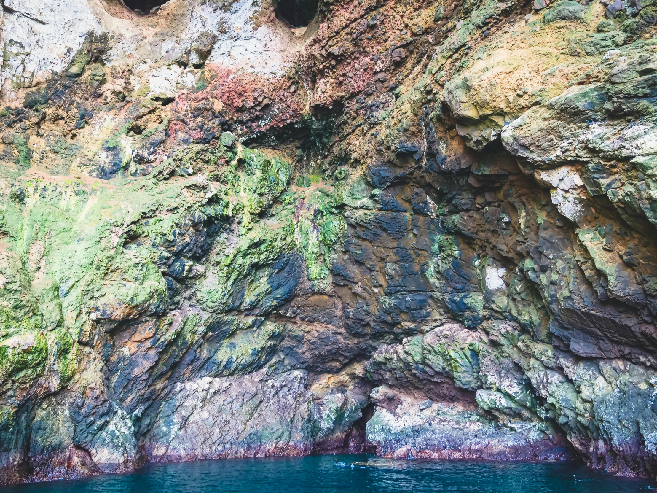 a group of people floating on top of a body of water, natural cave wall, pembrokeshire, blue and green colours, 🦩🪐🐞👩🏻🦳