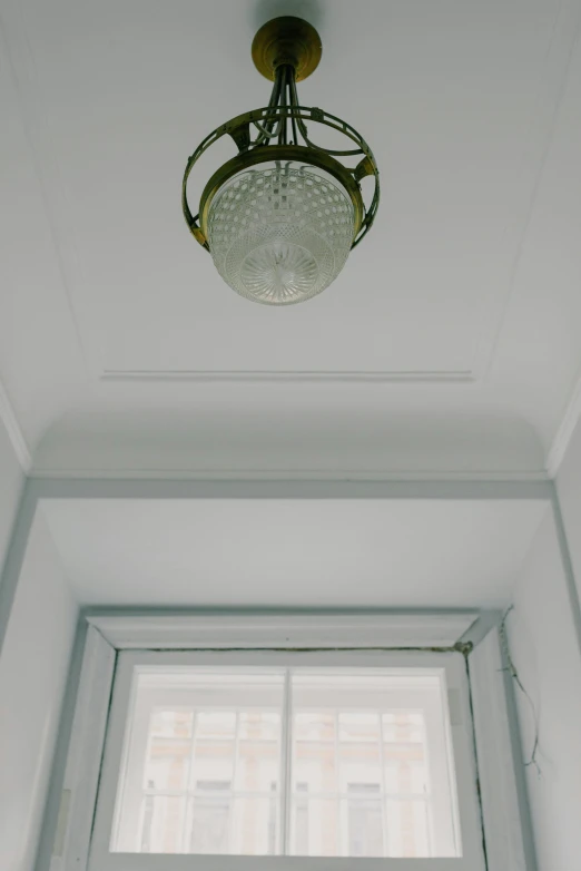 a light hanging from the ceiling in front of a window, inspired by Leandro Erlich, unsplash, ornate detail, neo - classical, recessed, entrance