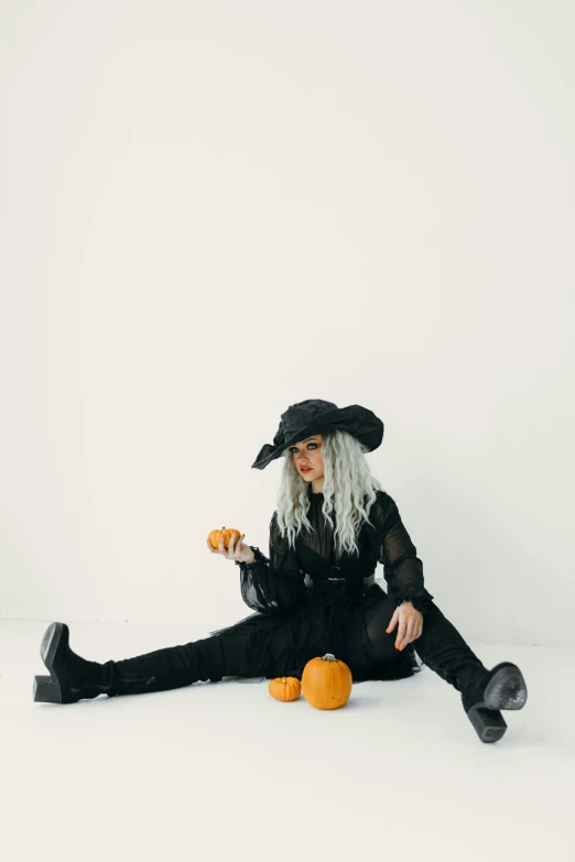 a woman in a witch costume sitting on the floor, pexels, on a white table, black and orange colour palette, white haired, gif