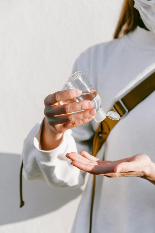 a woman wearing a face mask holding a glass of water, by Nicolette Macnamara, trending on pexels, urine collection bag, partially cupping her hands, apothecary, festivals