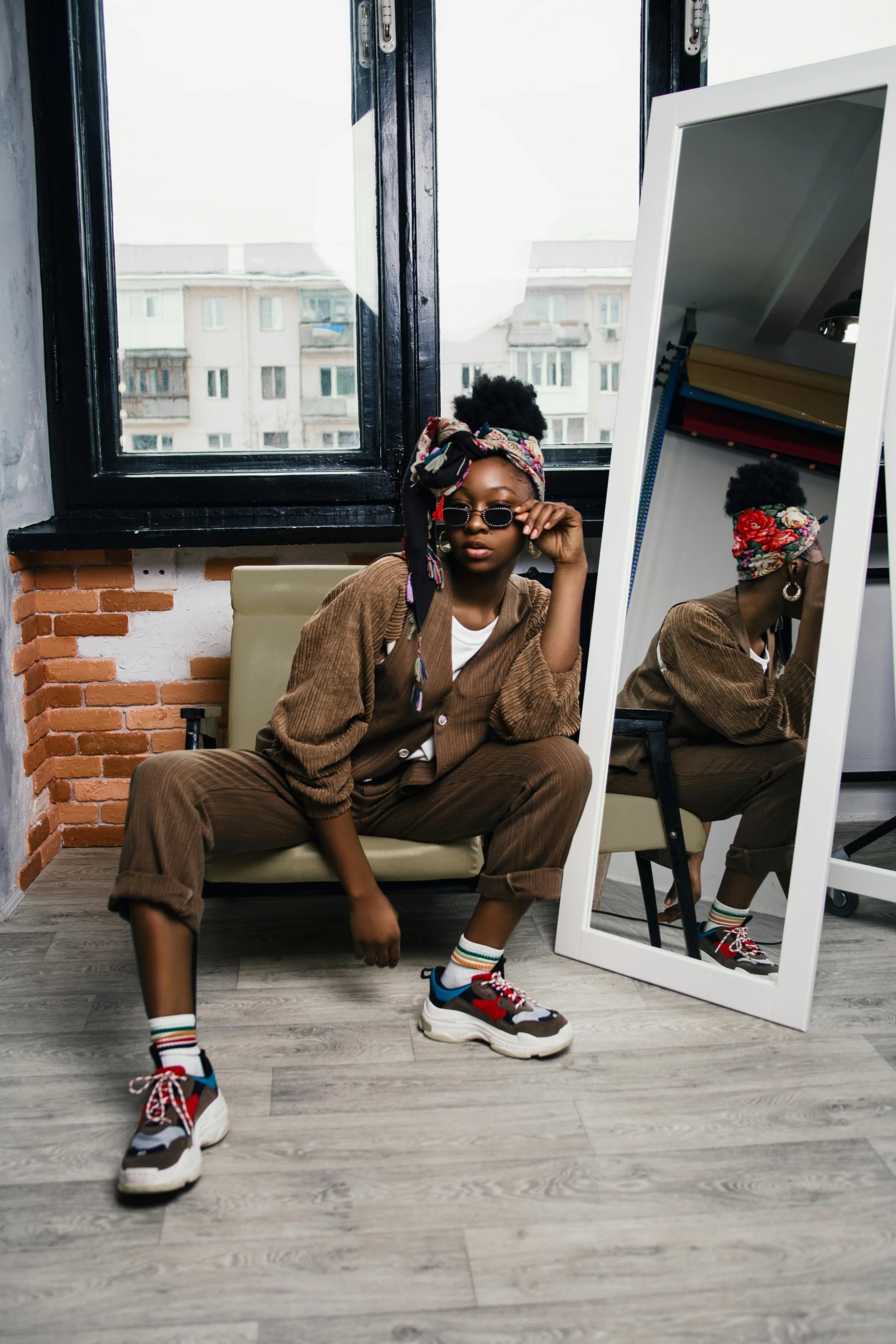 a man sitting on a chair in front of a mirror, by Lily Delissa Joseph, trending on pexels, afrofuturism, full body cute young lady, beret and sunglasses, wearing a baggy pajamas, sneakers