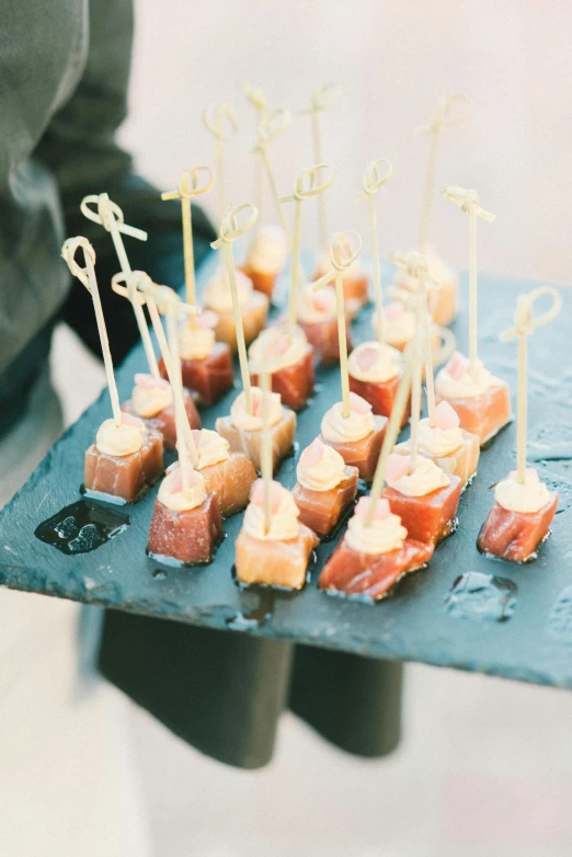 a person holding a tray with food on it, wedding, square, slate, school of fish