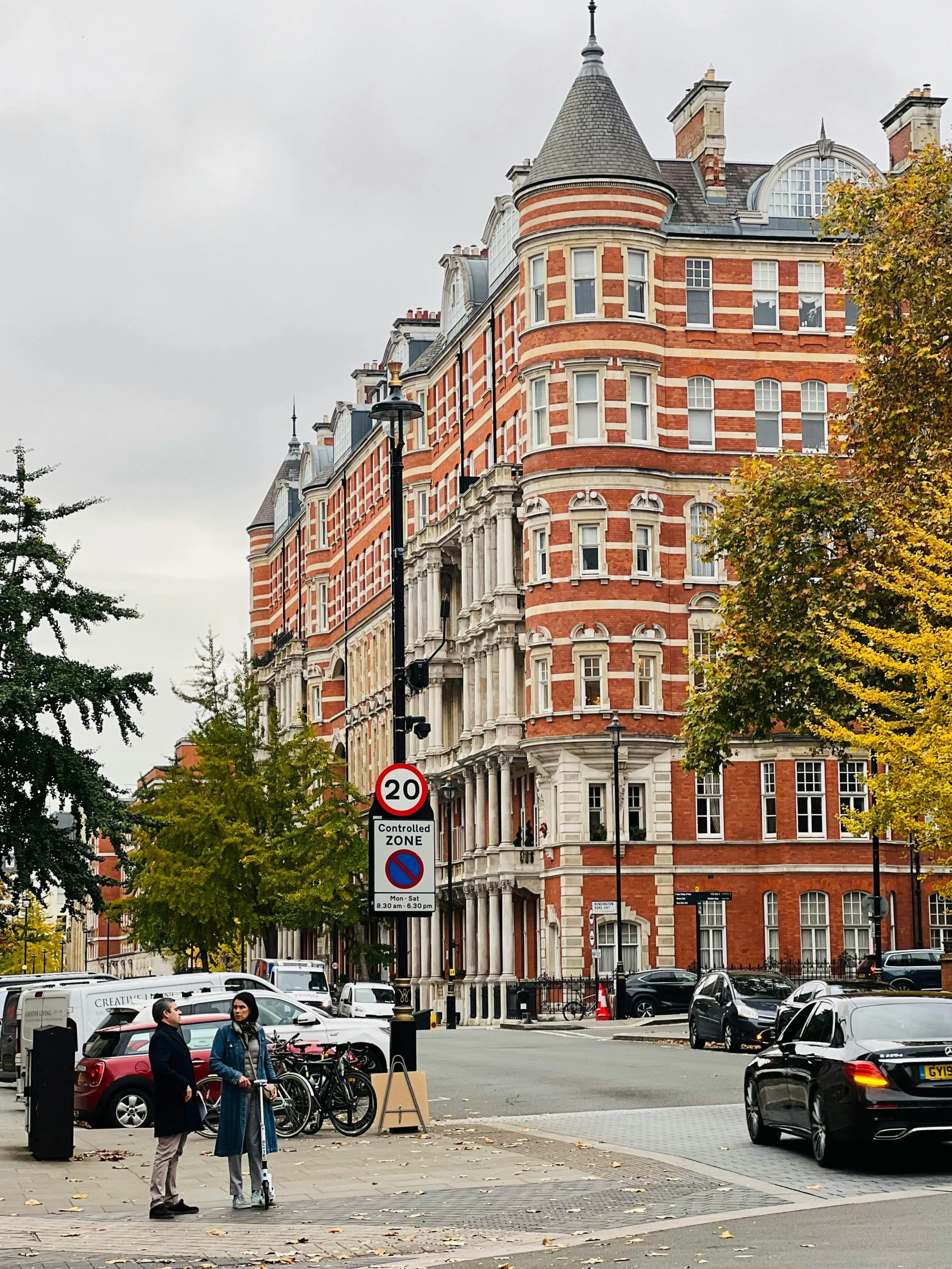 a group of cars driving down a street next to tall buildings, by Nina Hamnett, victorian buildings, during autumn, profile image