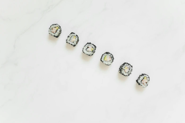 a row of sushi sitting on top of a white counter, inspired by Maki Haku, swarovski crystals, 6 pack, black opals, flat lay