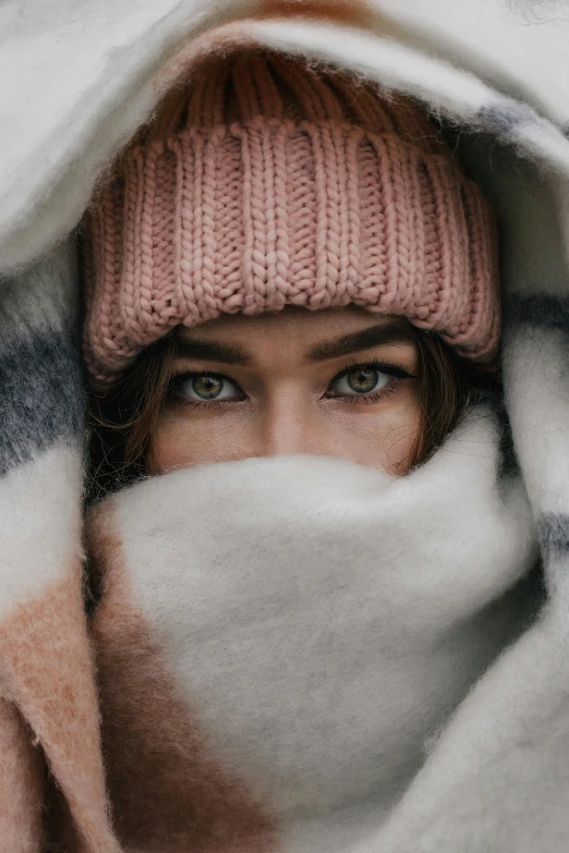 a woman is wrapped up in a blanket, trending on pexels, icy eyes, beanie, pink, hiding behind obstacles