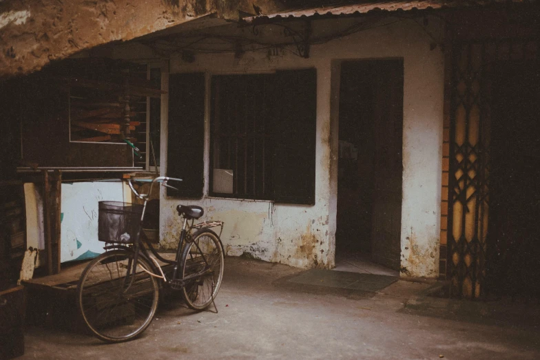 a bicycle parked in front of a building, a picture, inspired by Elsa Bleda, pexels contest winner, old asian village, faded and dusty, brown, dark dirty grungy streets
