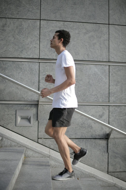 a man riding a skateboard down a flight of stairs, tan skin a tee shirt and shorts, running shoes, thumbnail, 1km tall