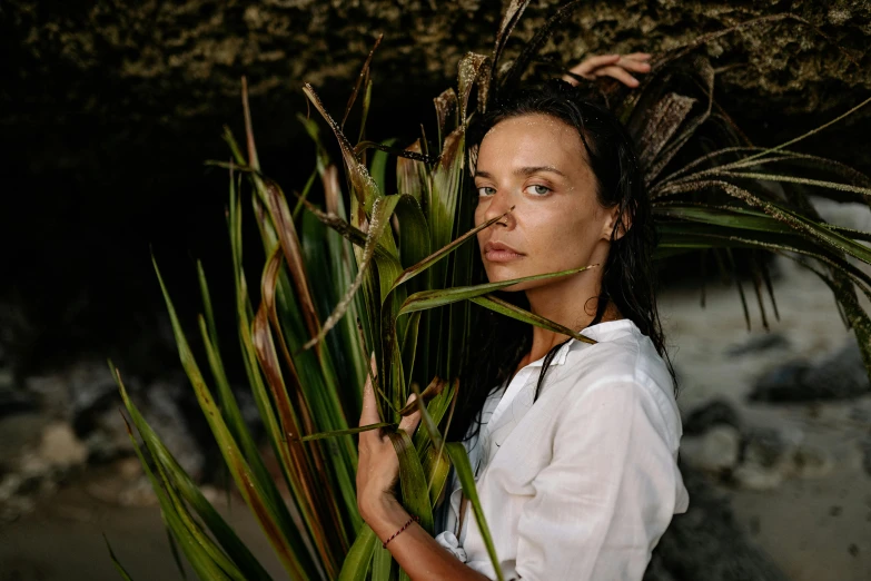 a woman standing next to a lush green plant, a portrait, unsplash, dafne keen, on the coast, avatar image, indigenous