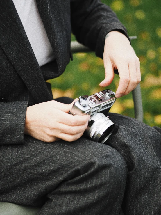 a person sitting in a chair holding a cell phone, a picture, inspired by Henri Cartier-Bresson, unsplash, happening, hasselblad medium format camera, autumn, close up shot from the side, well - dressed