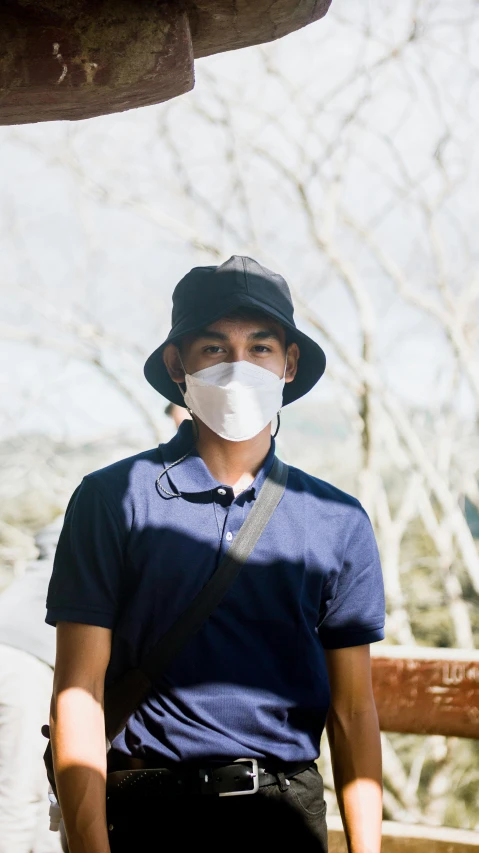 a man standing next to a giraffe wearing a face mask, a picture, unsplash, wearing a navy blue utility cap, asian human, clean shaven, pollution