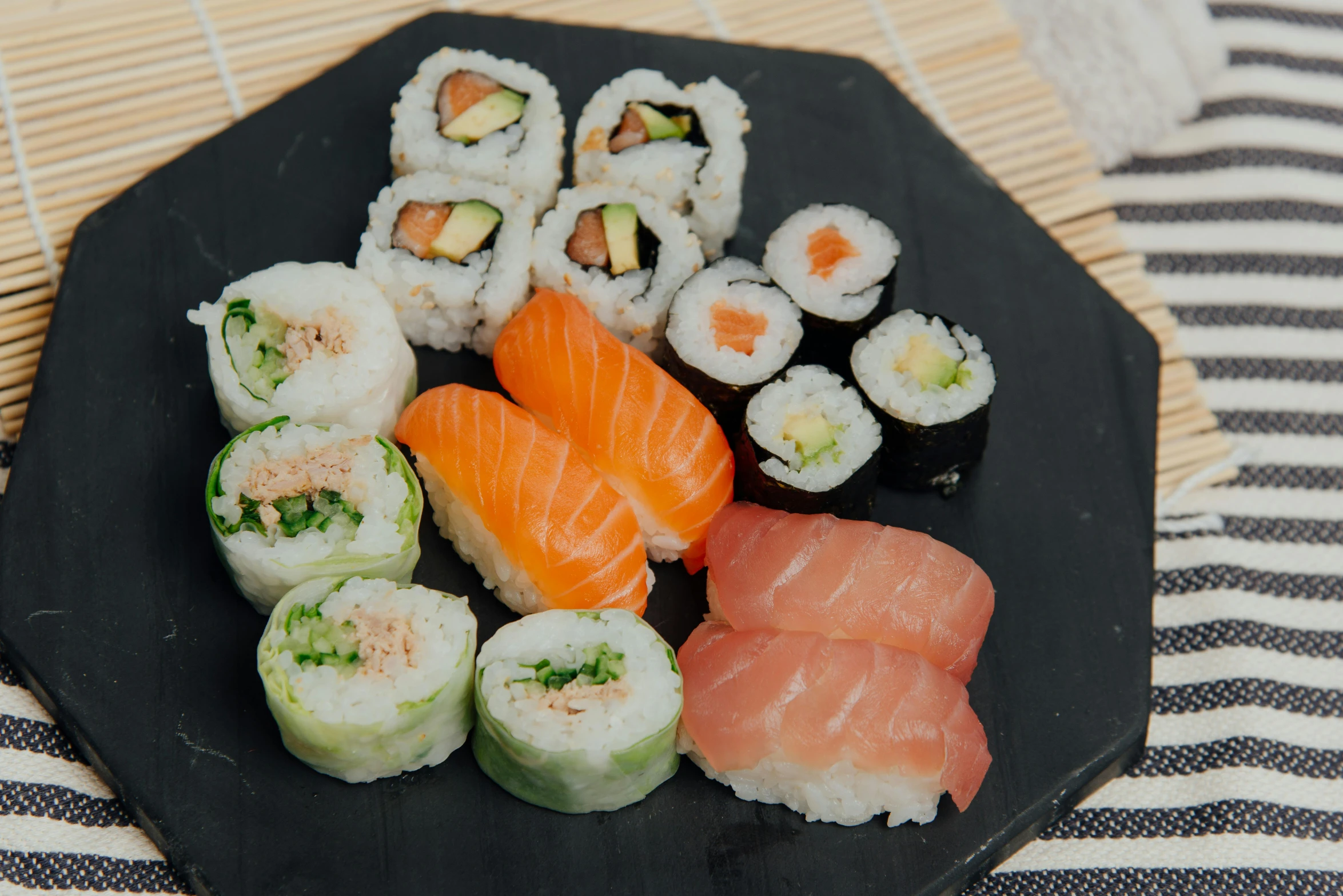 a black plate topped with different types of sushi, unsplash, mingei, 90's photo, fan favorite, 2000s photo, mediterranean