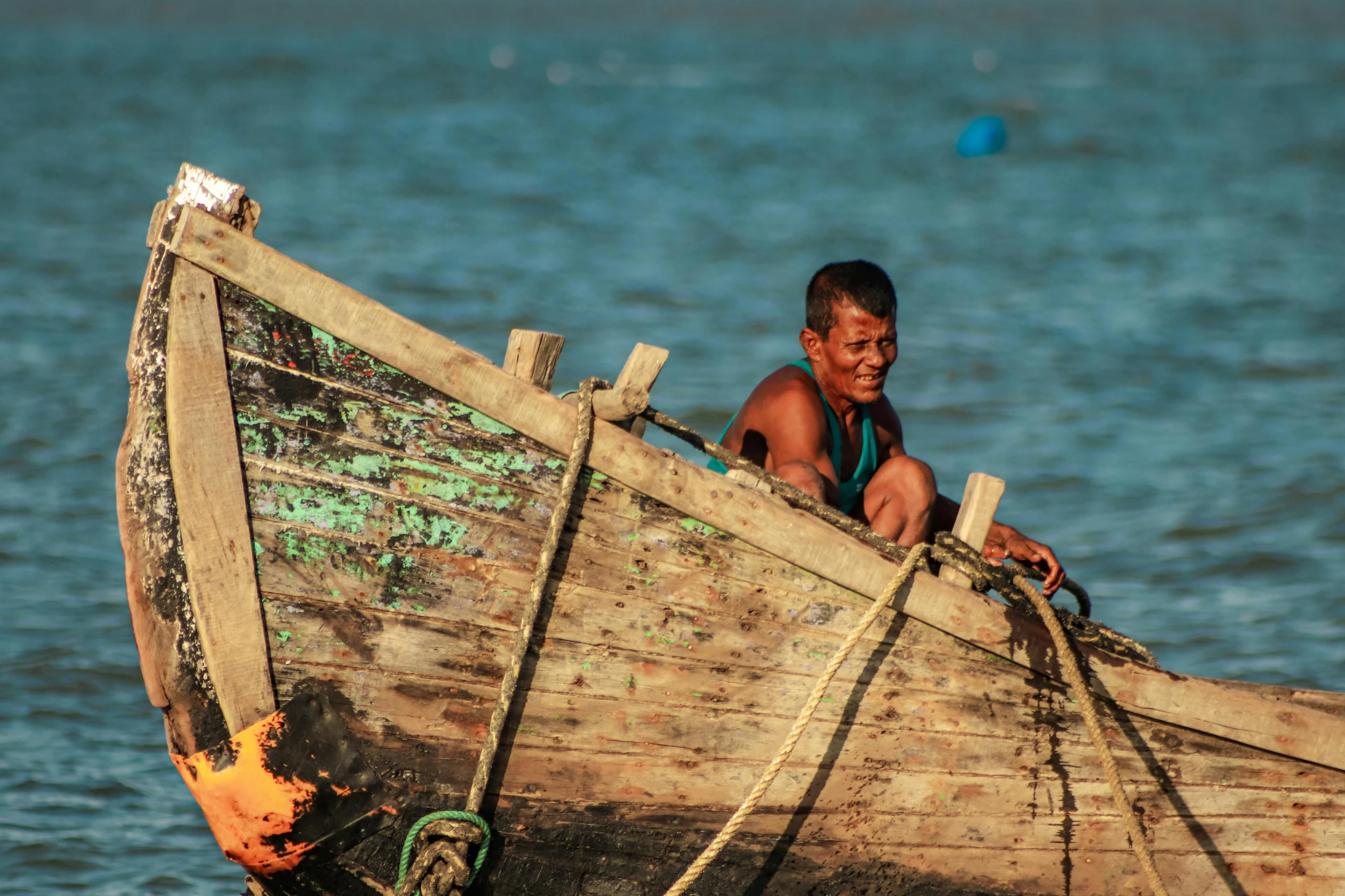 a man sitting on top of a wooden boat in the water, indigenous man, profile image, fishing village, documentary photo