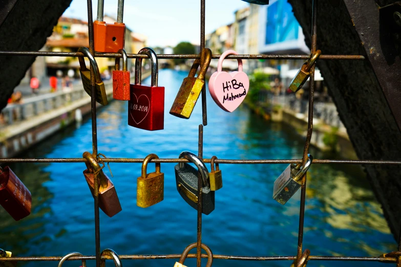 a number of padlocks attached to a fence, by Julia Pishtar, pexels contest winner, canals, colorful scene, 🦩🪐🐞👩🏻🦳, indigo and venetian red