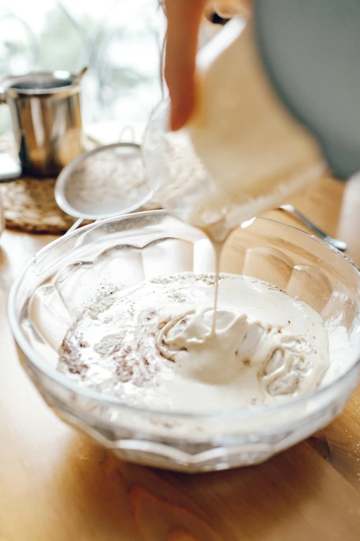 a person pouring milk into a bowl on a table, whipped cream, thumbnail, shimmering, epicurious