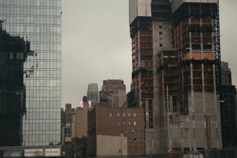 a group of tall buildings sitting next to each other, a photo, inspired by Thomas Struth, overcast gray skies, construction site, seen from a distance, joel sternfeld