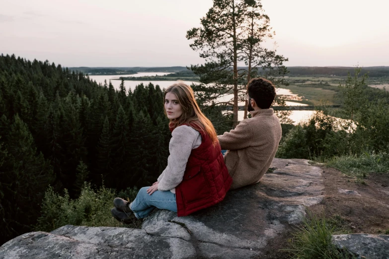 a man and a woman sitting on top of a rock, by Grytė Pintukaitė, pexels contest winner, hygge, looking across the shoulder, moviestill, finnish naturalism