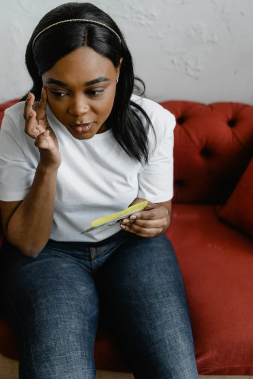 a woman sitting on a couch talking on a cell phone, trending on pexels, happening, contracept, black woman, devastated, holding scale