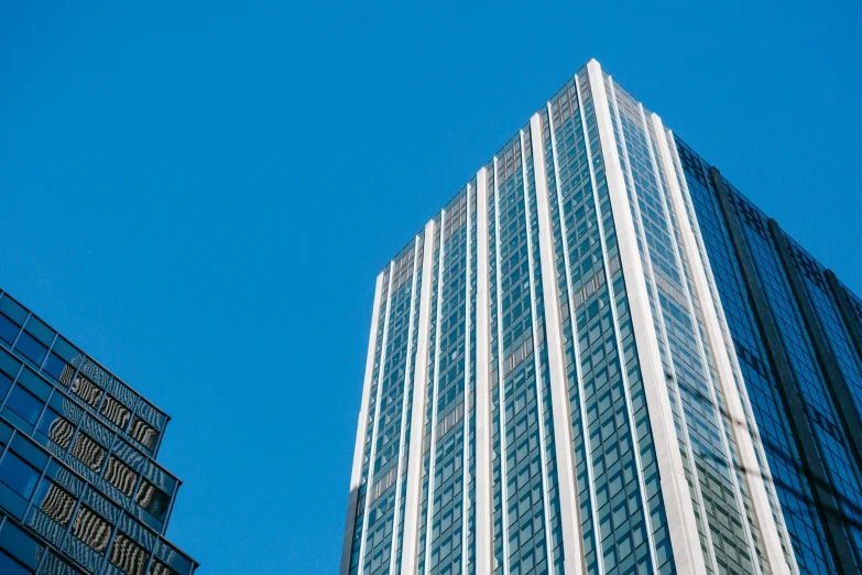 a tall building sitting in the middle of a city, azure blue sky, coper cladding, thumbnail, features