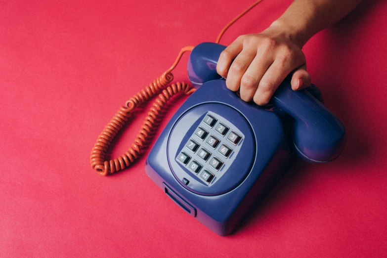 a close up of a person holding a telephone, by Julia Pishtar, trending on pexels, pop art, light red and deep blue mood, 70s design, blue and purple scheme, teenage engineering moad