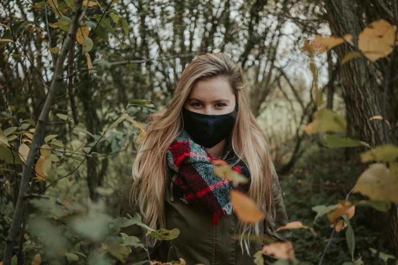 a woman wearing a face mask in the woods, by Emma Andijewska, pexels contest winner, black bandana mask, young blonde woman, the autumn plague gardener, wearing fluffy black scarf