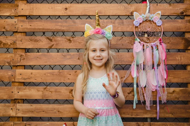 a little girl standing in front of a wooden fence, unicorn horn, fully decorated, 15081959 21121991 01012000 4k, dreamcatchers