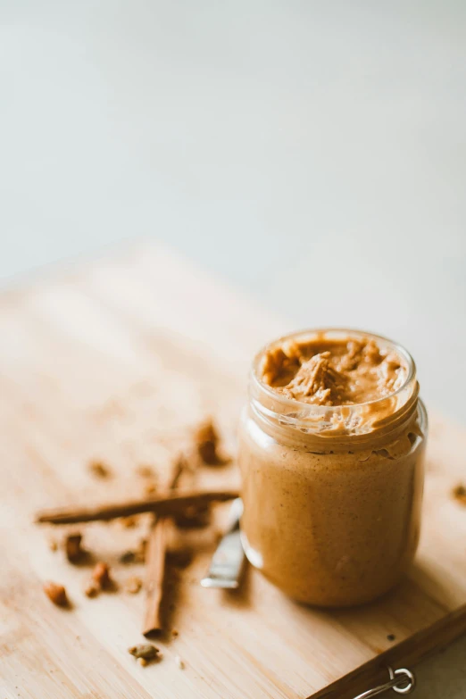 a jar of peanut butter sitting on top of a cutting board, unsplash, cinnamon skin color, background image, vine, thumbnail