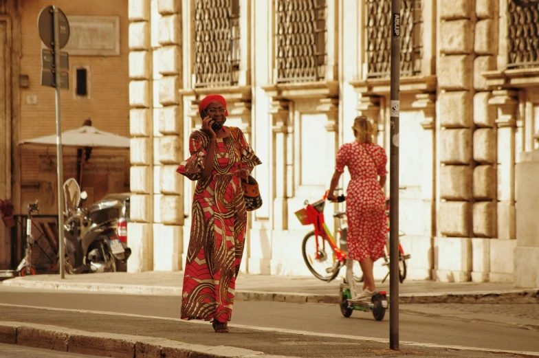 a woman walking down a street talking on a cell phone, by Nina Hamnett, pexels contest winner, renaissance, wearing an african dress, style blend of the vatican, wearing red attire, patterned clothing