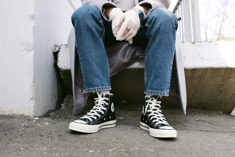 a man sitting on the steps of a building, trending on pexels, converse, wearing denim, sitting in a chair, black canvas