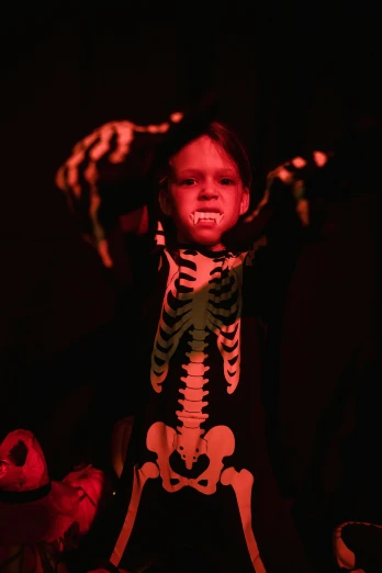 a child dressed up in a skeleton costume, by Gwen Barnard, casting evil spell, slide show, concert, screaming