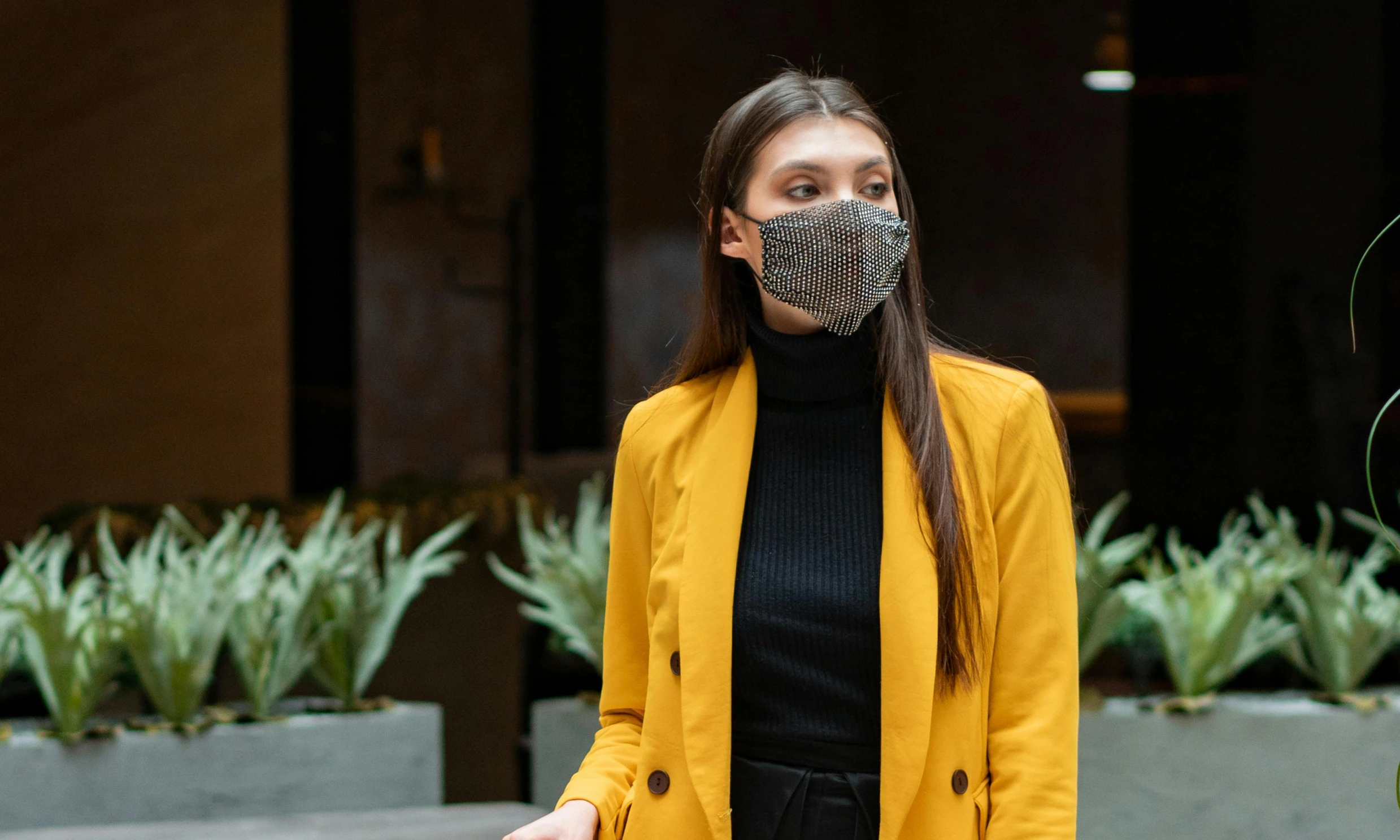 a woman wearing a face mask in front of a building, trending on pexels, renaissance, yellow and charcoal leather, people outside walk, silver and yellow color scheme, wearing jacket