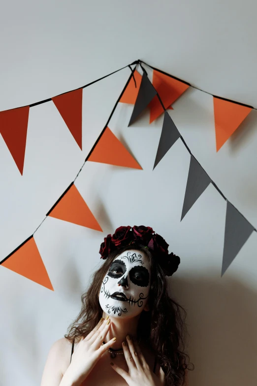 a woman in day of the dead makeup posing for a picture, by Arabella Rankin, conceptual art, red pennants, gray and orange colours, still life photo of a backdrop, papercraft