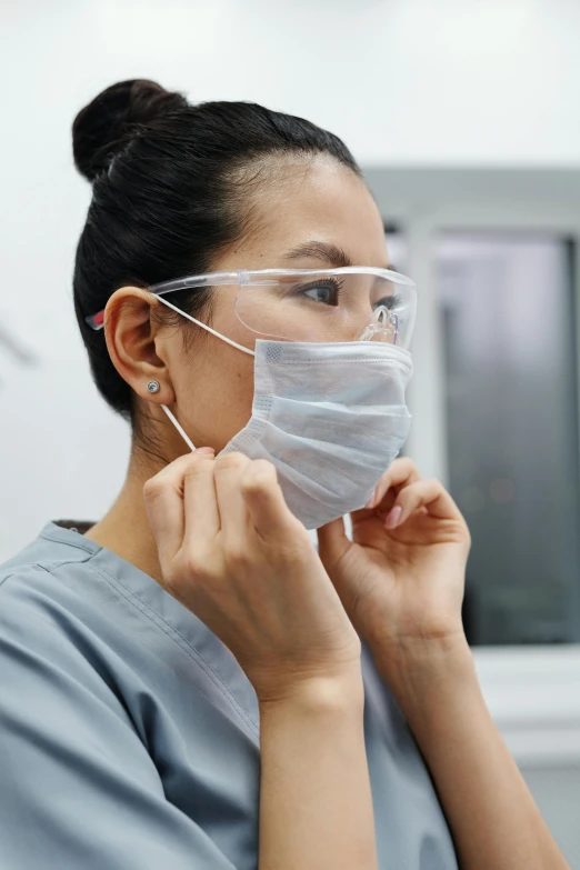 a woman in scrub gear putting on a mask, glasses |, asian human, profile image, grey