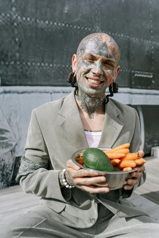 a man holding a bowl of carrots and an avocado, an album cover, inspired by James Bolivar Manson, face tattoo, 2019 trending photo, rat man, adar darnov