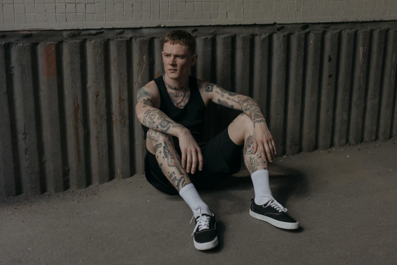 a man with tattoos sitting on the ground, inspired by Seb McKinnon, pexels contest winner, yung lean, she is wearing a black tank top, high soles, structure : kyle lambert