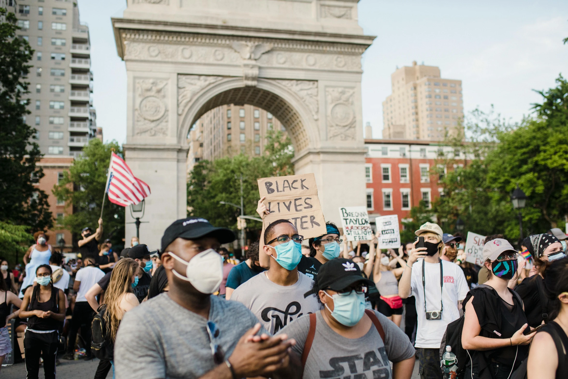 a group of people walking down a street with masks on, a photo, pexels, black arts movement, protesters holding placards, ny, a park, background image