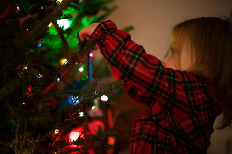 a little girl is decorating a christmas tree, by Julia Pishtar, pexels, tartan cloak, lights off, thumbnail, low detail
