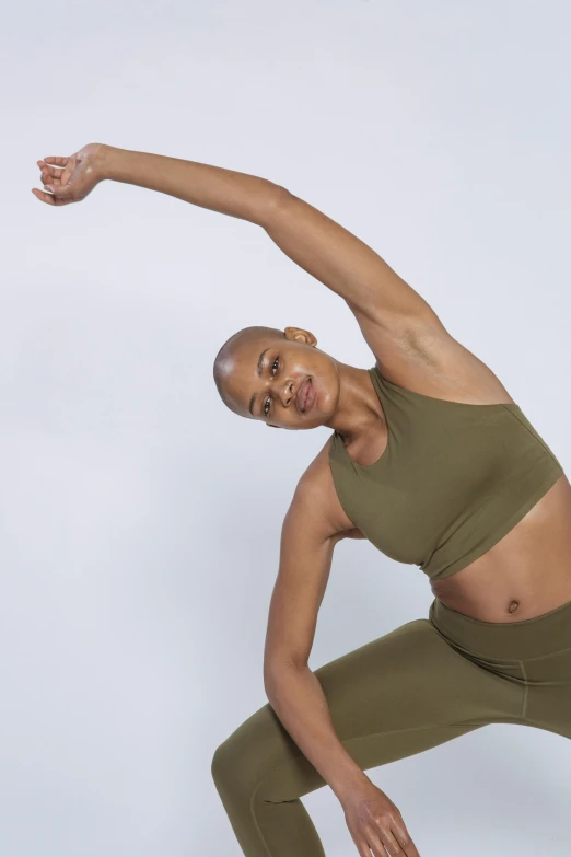 a woman doing a yoga pose against a white background, by Dulah Marie Evans, featured on instagram, renaissance, olive green, smooth contours, arms out, army