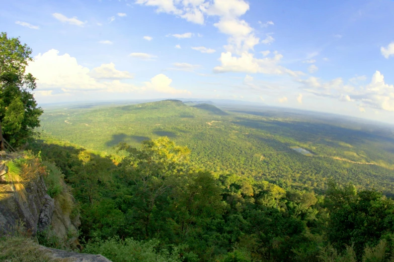 a person riding a bike on top of a mountain, angkor thon, lush forest in valley below, listing image, panoramic