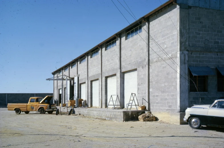a truck parked in front of a building, concrete building, in a warehouse, restored photo, exterior view