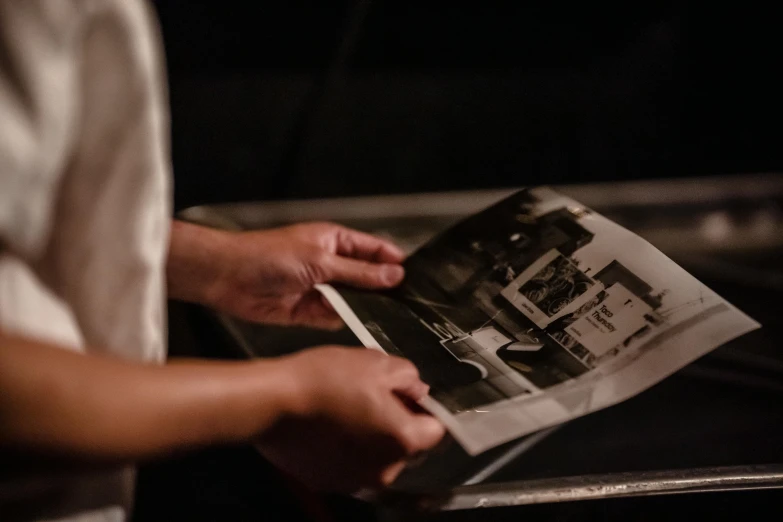 a close up of a person holding a magazine, inspired by Roy DeCarava, unsplash, mezzotint, performing, production photo, a seance