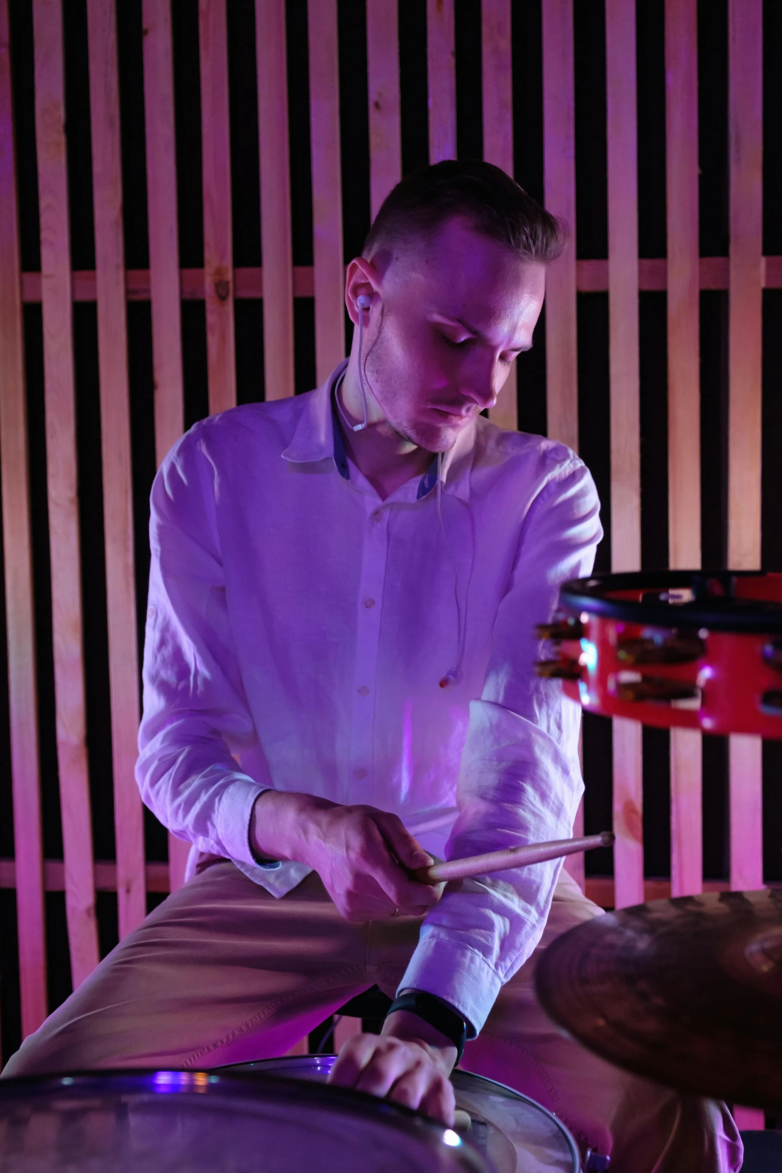 a man in a white shirt is playing drums, by Julia Pishtar, kinetic art, atmospheric red lighting, vitalik buterin, plating, concerned